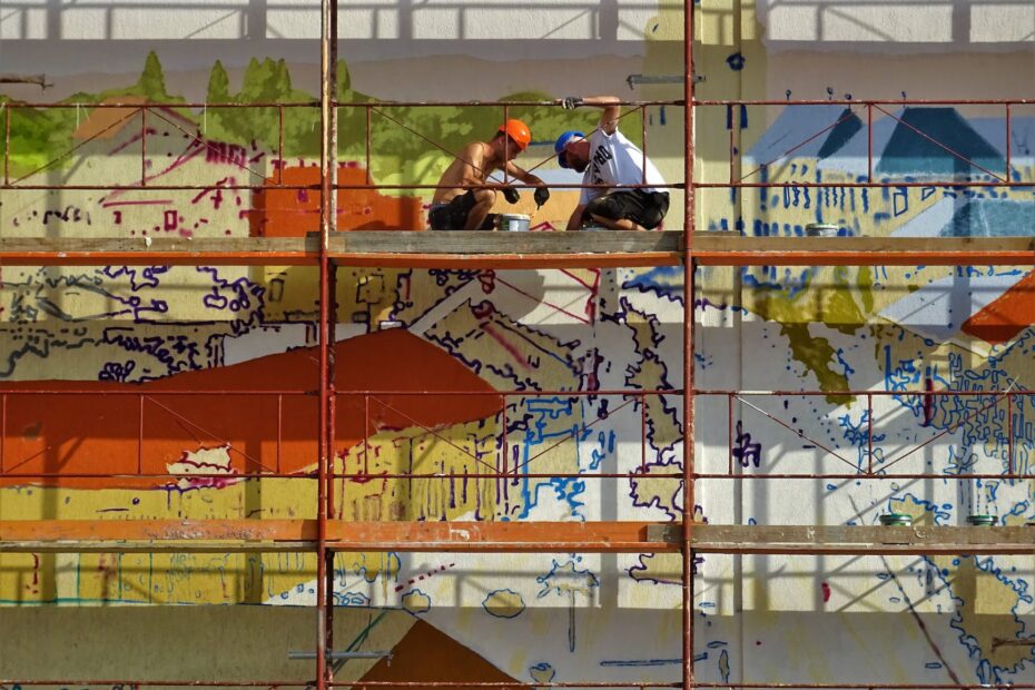 two person on scaffolding painting wall